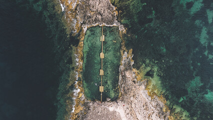 Qawra Pool on Malta's northern coast is a stunning natural sea pool carved into the rocky shoreline. Captured from above by drone, this picturesque location boasts crystal clear, turquoise waters set  © Tomasz