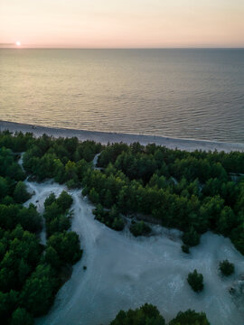 Aerial view of serene forest, tranquil sea, and sunset over Baltic Sea, Leba, Poland.