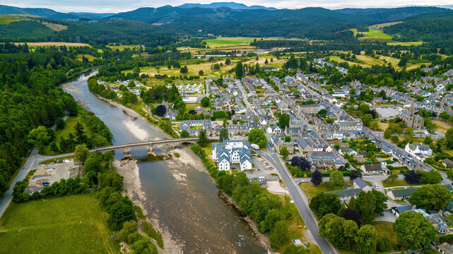 Aerial view of picturesque town by River Dee with mountains and lush greenery, Ballater, Scotland, United Kingdom.