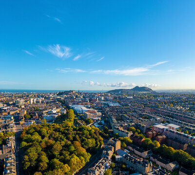 Aerial view of vibrant cityscape with mountains and greenery, Edinburgh, Scotland.
