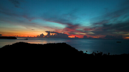 Aerial view of serene sunrise over island with tropical sky and calm ocean, Fiji.