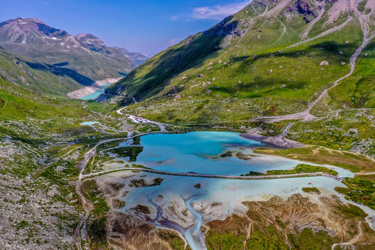 Aerial view of vibrant turquoise Moiry Glacier Lake amidst majestic alpine mountains, Anniviers, Switzerland.