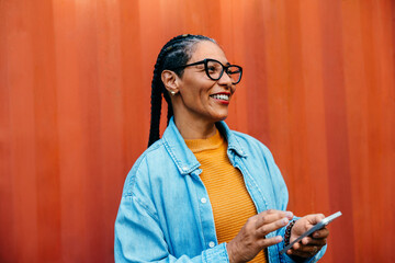 Latin American businesswoman using smartphone in vibrant setting