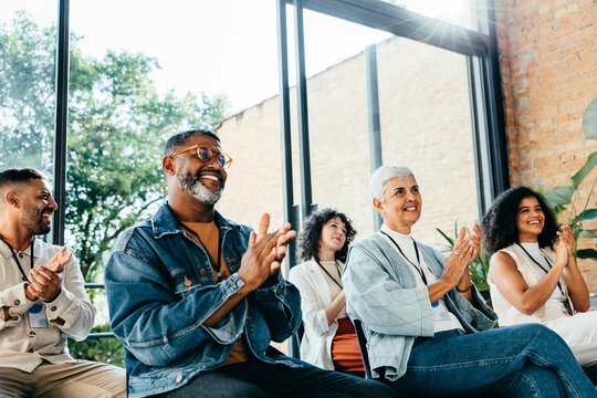 Diverse group of people attending a business meeting, happily clapping and smiling
