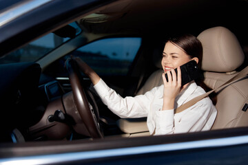 Woman, cell phone, car, steering wheel a woman is talking on a cell phone while sitting in a car,...