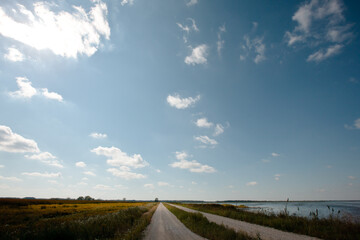 The mid-September afternoon sun is blocked briefly by the clouds, illuminating only a small portion of Dike Road to be sunlit, with the Horicon National Wildlife Refuge, near Kekoskee, Wisconsin.