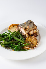 This savory dish features baked green beans with onions and tender mackerel, served on a plate against a white background, offering a healthy and balanced gourmet meal