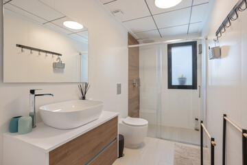 A sleek, modern bathroom featuring a glass-enclosed shower, a vessel sink, wooden cabinetry, and contemporary fixtures for a clean look.