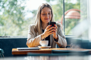 Beauty young businesswoman texting with her mobile phone in the coffee shop