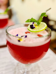 Close up of red mocktail with green garnish and lime.