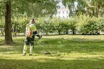 Lawn mowers cut the grass in a city park.