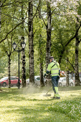 Obraz premium Lawn mowers cut the grass in a city park.