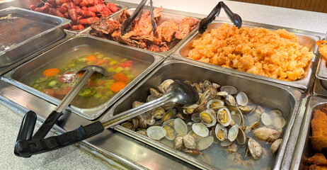 A buffet selection featuring a variety of seafood, fried food, and vegetable soup