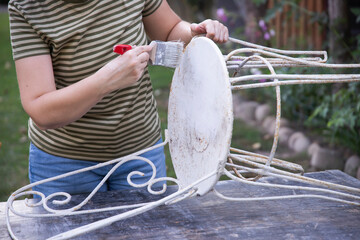 Painting an wrought iron chair outdoors, an eco-friendly re-use business.