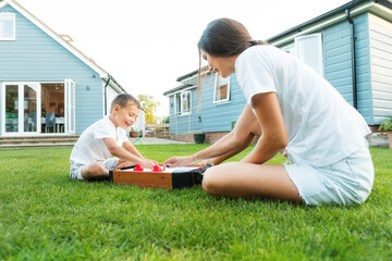 Joyful little boy and his young mother are playing portable air hockey in the garden. Fun Playing...