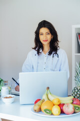 Positive Indian female nutritionist having online consultation with client at office desk with...