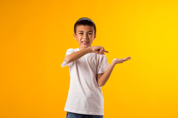 Smiling child boy pointing to an empty palm on yellow background. Advertisement concept