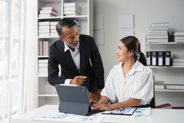 Senior manager demonstrating business strategy on digital tablet to young female employee during a meeting