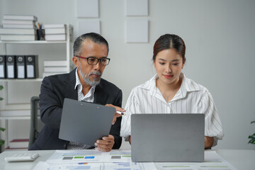 Seasoned supervisor sharing a document with a new intern and pointing to something on a laptop screen