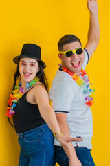 young latin couple, celebrating with a lot of joy, putting their backs together with a yellow background.