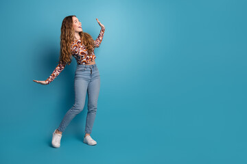 Full size photo of nice young girl dance empty space ad wear top isolated on blue color background
