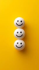 Obraz premium Three ping pong balls with smiley faces on yellow background, cheerful concept