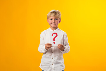 Portrait of kid boy holding question mark card in hand. Education and curiosity concept