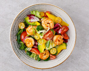 Salad with shrimps in sweet and sour sauce with mango and avocado. on a gray background