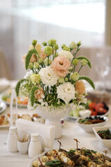 The festive table in the restaurant is decorated with a beautiful bouquet of white flowers.