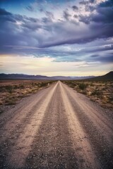 An empty dirt road in a desert landscape under a sunset, offering a sense of adventure and tranquility.