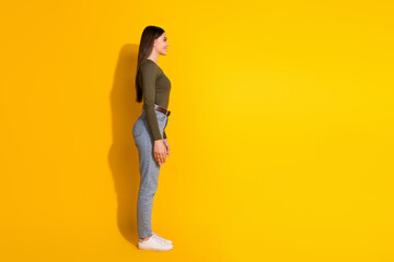 Full size photo of pretty teenager girl profile look empty space wear trendy khaki outfit isolated on yellow color background