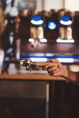 photo of a barista holding a portafilter, working in the coffee shop or restaurant. 