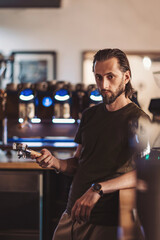 photo of a barista holding a portafilter, working in the coffee shop or restaurant. 