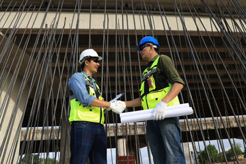 Engineers on construction site. Manager and contractor shaking hands and smiling with the steel bar  infrastructure  of the bridge in background