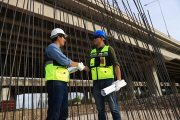 Engineers on construction site. Manager and contractor shaking hands and smiling with the steel bar...