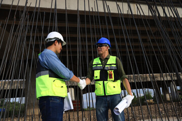 Engineers on construction site. Manager and contractor shaking hands and smiling with the steel bar...
