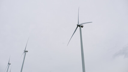 A row of tall wind turbines against a cloudy sky, symbolizing renewable energy and sustainable technology.