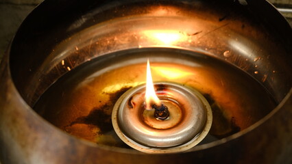 A serene oil lamp with a gentle flame, illuminating the surroundings and creating a warm, tranquil...