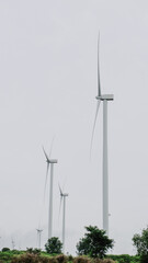 Three wind turbines stand tall against a cloudy sky, showcasing sustainable energy generation in a serene landscape.