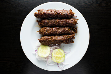 Beef Seekh Kabab with cucumber and onion salad served in dish isolated dark background top view of indian spices, bangladeshi and pakistani food