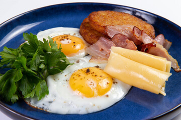 Fried eggs, cheese and hash brown in a plate