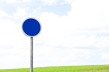 Blue Road Sign With White Arrow Pointing Up In A Grass Field