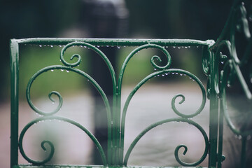 Rain Droplets on Green iron chair detail.  vintage metal fence. abstract metallic background. Rainy...