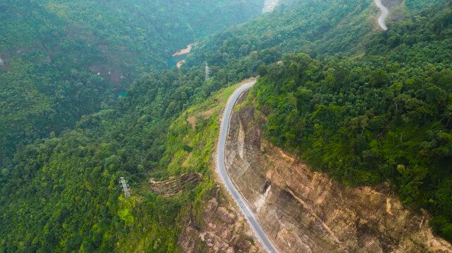 Aerial view of a dangerous winding road along a lush green mountain cliff leading to the Ha Giang Loop in Vietnam