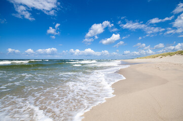 Empty, sandy beach and sea waves by sunny day