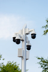 There are many CCTV cameras on a pole in the park.