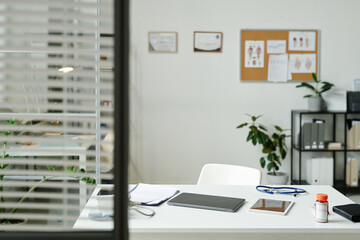Laptop, tablet, medical document, bottle of pills, stethoscope and tonometer lying on workplace of modern general practitioner