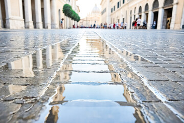 Fototapeta premium Wet cobblestones reflecting the sky and buildings in a city street