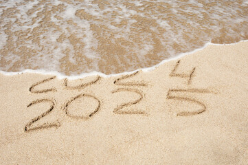 Inscription 2024 and 2025 numbers written on sand.  New Year 2025 replace 2024. Concept on the sea beach