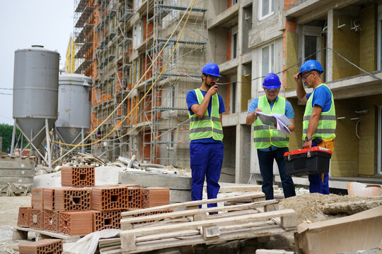 Engineer coworker in protective workwear discussing while working together at construction site